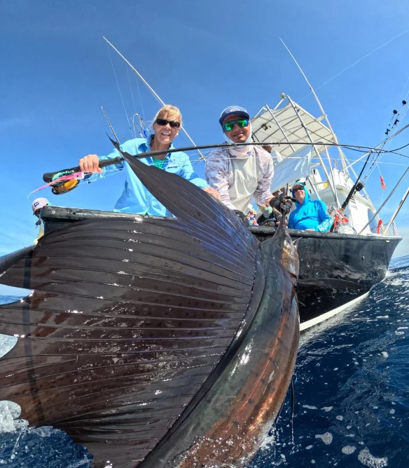 Excited angler holding a large pacific sailfish caught on a fly rod in Guatemala, showcasing the thrill of fishing in exotic locations. The image captures the beauty of the ocean and the joy of a successful catch.