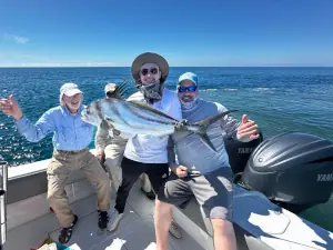 Group posing with a roosterfish on the beach in Costa Rica