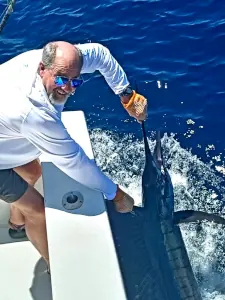 Angler holding a sailfish alongside the boat offshore in Costa Rica
