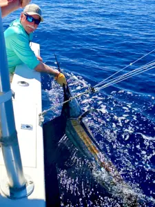 Angler in a green shirt with a sailfish at the boat in Costa Rica
