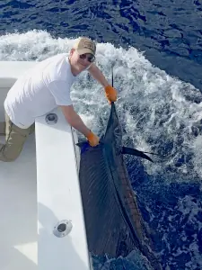 Angler with orange gloves holding a sailfish at the boat in Costa Rica