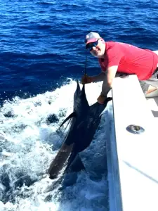 Angler in a red shirt holding a sailfish beside the boat in Costa Rica