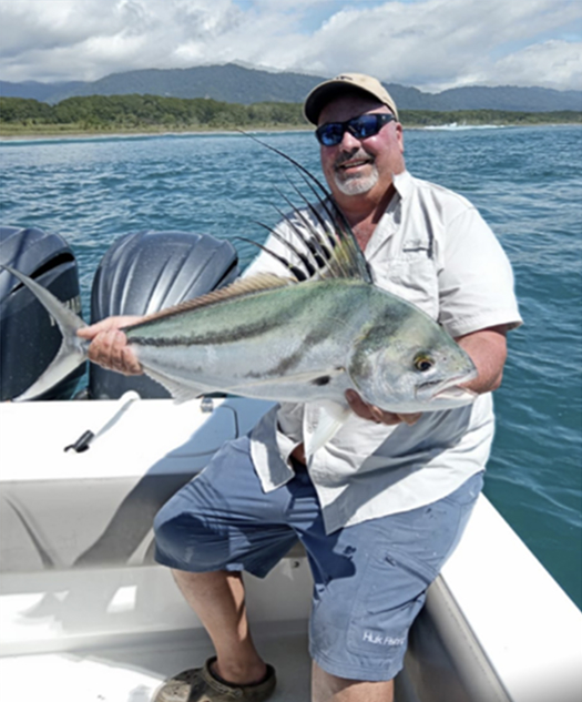 A fisherman on a boat holding a large fish caught in Costa Rica. The image captures the thrilling beauty of fishing in Costa Rica.