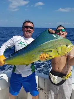 Two fishermen on a boat holding a large doradao caught in Costa Rica. The image captures the thrilling beauty of fishing in Costa Rica.