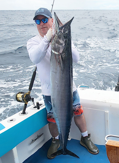A fisherman on a boat holding a large fish caught in the Galapagos Islands. The image captures the thrilling beauty of fishing in the Galapagos.