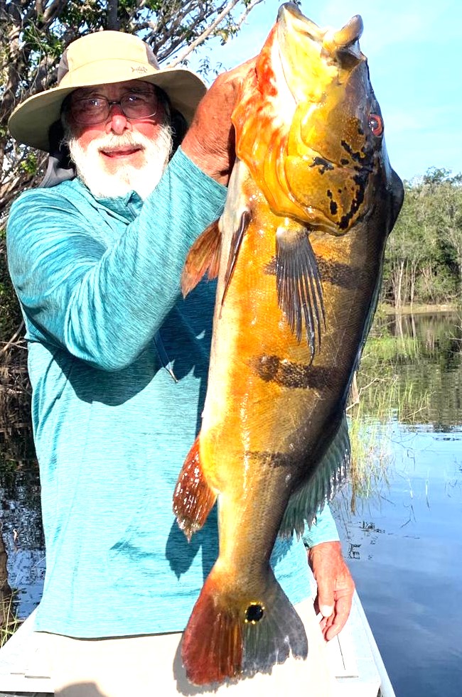 A fisherman holding a large fish caught in a scenic location in Brazil. The image captures the thrilling beauty of fishing in Brazil.