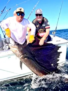 George holding a large sailfish alongside the boat in Guatemala