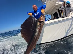 Angler in a blue shirt holding a sailfish alongside the boat in Guatemala