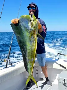 Angler in a hooded shirt holding a bright dorado in Guatemala