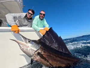 Two fishermen holding a large sailfish alongside the boat in Guatemala