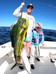 Two generations of anglers holding a dorado in Guatemala