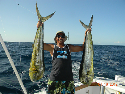An excited angler holding two dorado fish in Panama